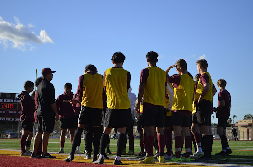 The soccer team is captured in a strong moment of focus as they focus and listen on their coach.